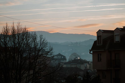 Houses and trees against sky during sunset