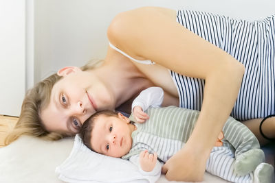 Portrait of mother with baby lying on bed at home
