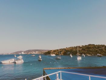 Sailboats moored in sea against clear sky