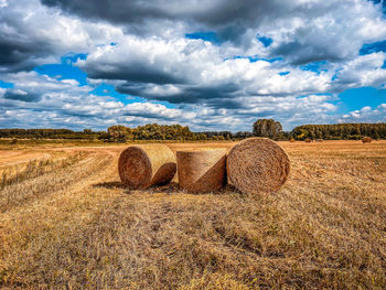 Hay bales on field against sky