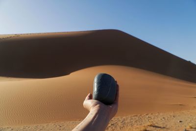 Close-up of hand holding sand against clear sky