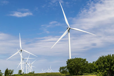 Low angle view of wind turbines against sky