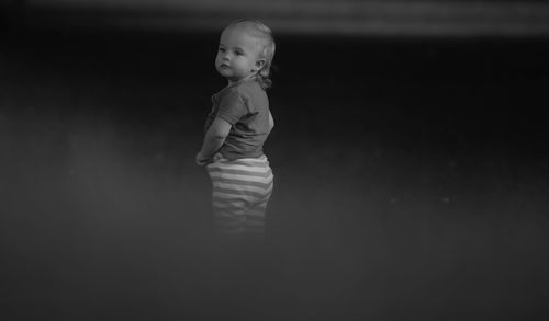 Girl looking away while standing in darkroom