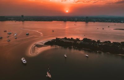 High angle view of city by sea against sky during sunset