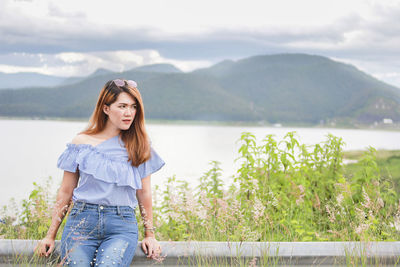 Portrait of beautiful young woman against mountains