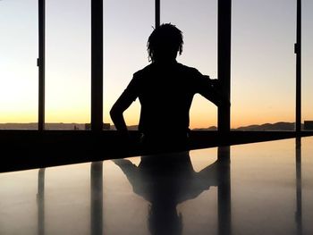 Rear view of silhouette woman standing against sky during sunset