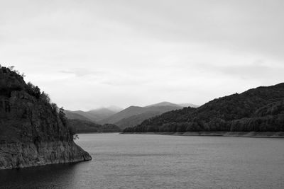 Scenic view of river by mountains against sky