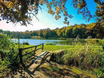 Scenic view of field by lake against sky
