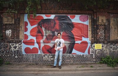 Full length of woman standing on graffiti wall