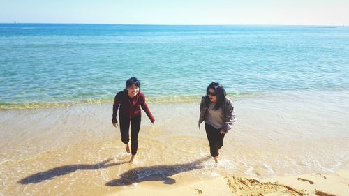 Women standing on beach against sea