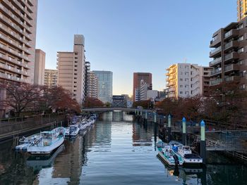 Boats in canal amidst buildings in city against clear sky