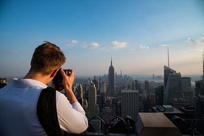 Rear view of man photographing empire state building and cityscape