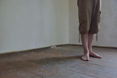Low section of man standing on hardwood floor at home