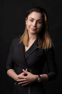 Portrait of a smiling young woman against black background