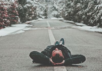 Man lying down on road during winter