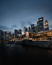Illuminated buildings in city against sky at dusk