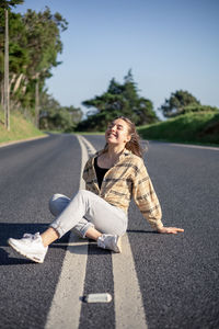 Portrait of young woman sitting on road