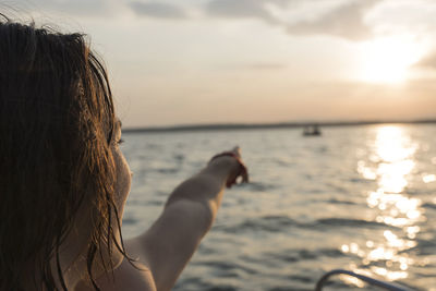 Woman looking at sea against sky during sunset