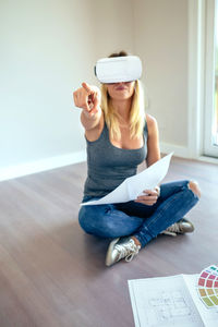 Woman wearing virtual reality simulator while sitting at home