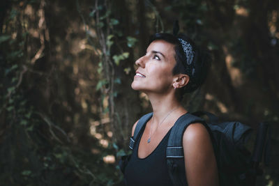 Woman looking away while standing in forest