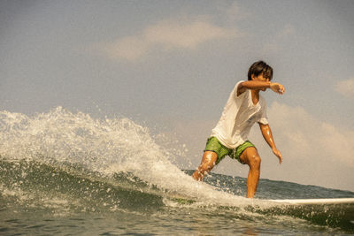 Full length of boy splashing water in sea