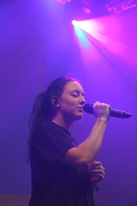 Side view of young woman with arms raised