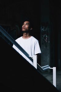 Young man standing by railing at home