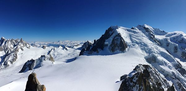 Scenic view of snow covered mountains against clear blue sky