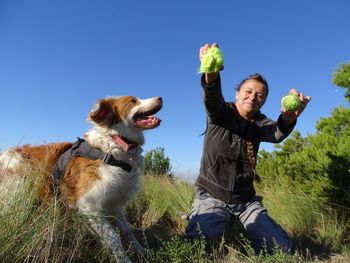Woman and dog playing with balls on land