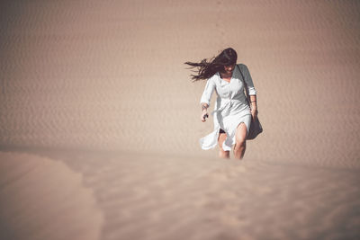 Full length of woman with umbrella on sand