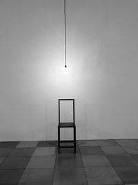 Empty chair on tiled floor against sky