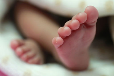 Low section of child lying on bed