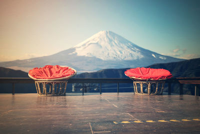 Chairs made of rattan and upholstery fabrics in red on wooden terrace with mount fuji background.