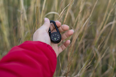 Hand picking up a black compass in the woods.