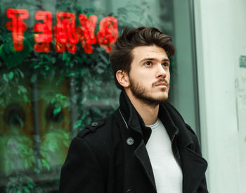 Thoughtful young man standing against window