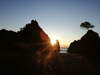 Silhouette rocks against clear sky during sunset