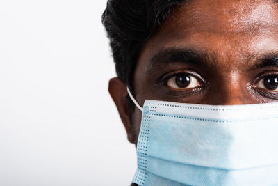 Close-up portrait of man wearing mask against white background