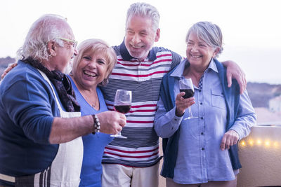 Cheerful senior friends standing at balcony during party