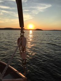 People sailing on sea against sky during sunset