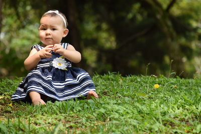 Cute baby girl sitting on field