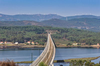 Railroad on a bridge over ria de arousa, catoira, galicia, spain, and wind turbines on the mountains