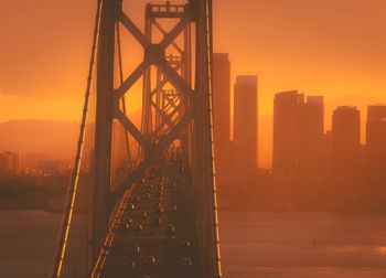 Low angle view of bridge and buildings against sky during sunset