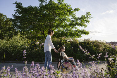Mother pushing daughter with disability sitting in wheelchair at park
