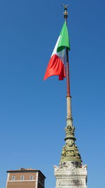 Low angle view of flag on building against blue sky