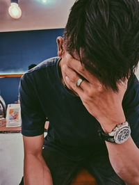 Midsection of young man looking down while sitting on wall