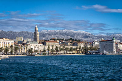 City at waterfront against blue sky