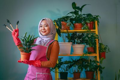 Portrait of a smiling young woman holding potted plant