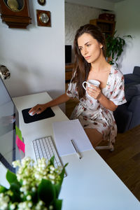 Woman having drink while working at home