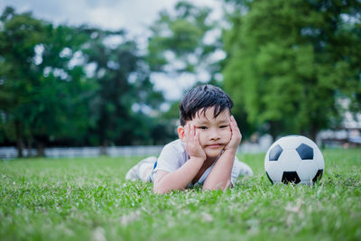 Portrait of boy with ball on grass
