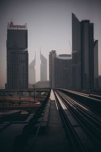 Railroad tracks by buildings against sky in city